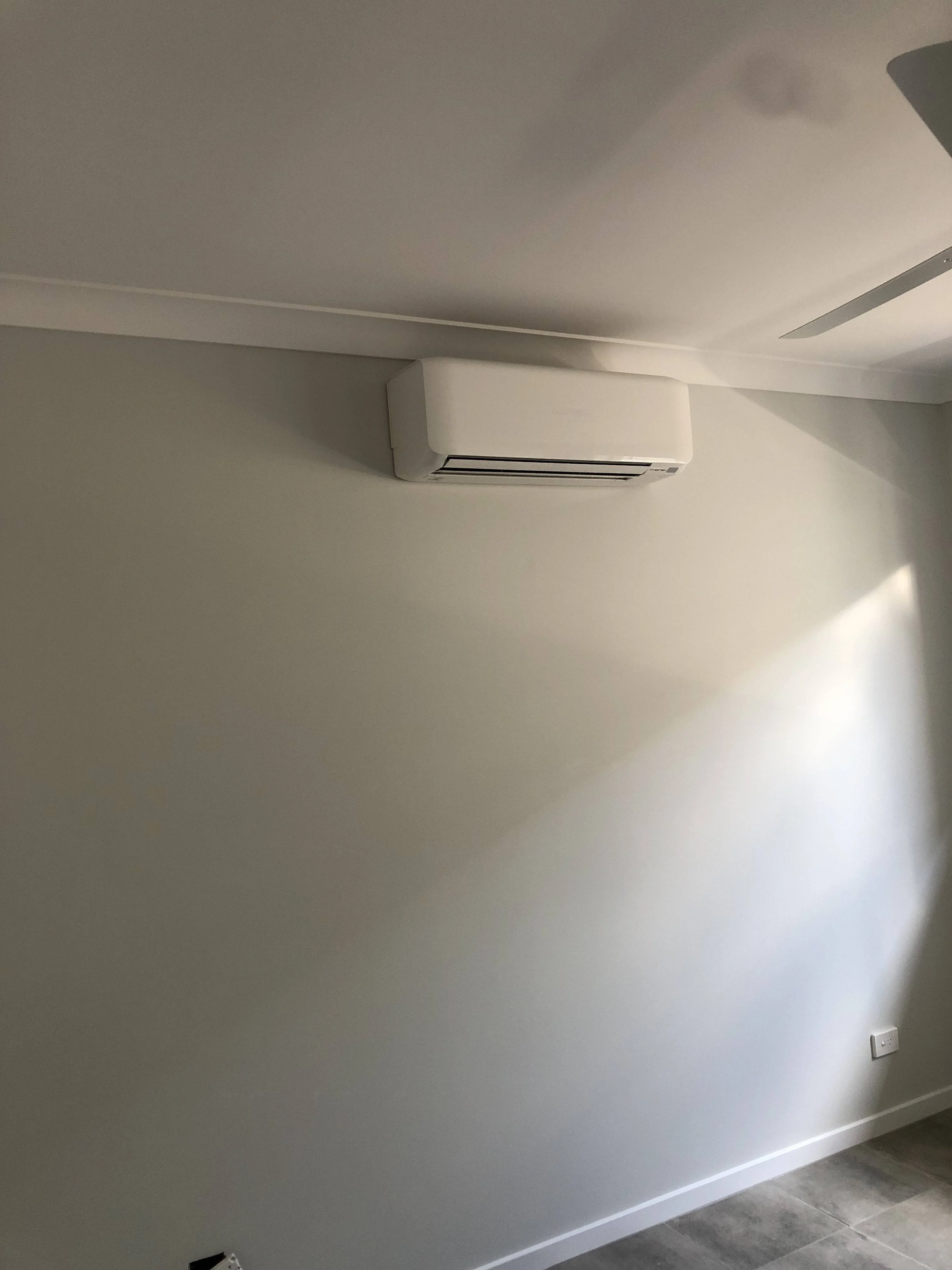 Ideal split system air conditioning layout for a Melbourne business with a white unit mounted high in a neutral-toned room